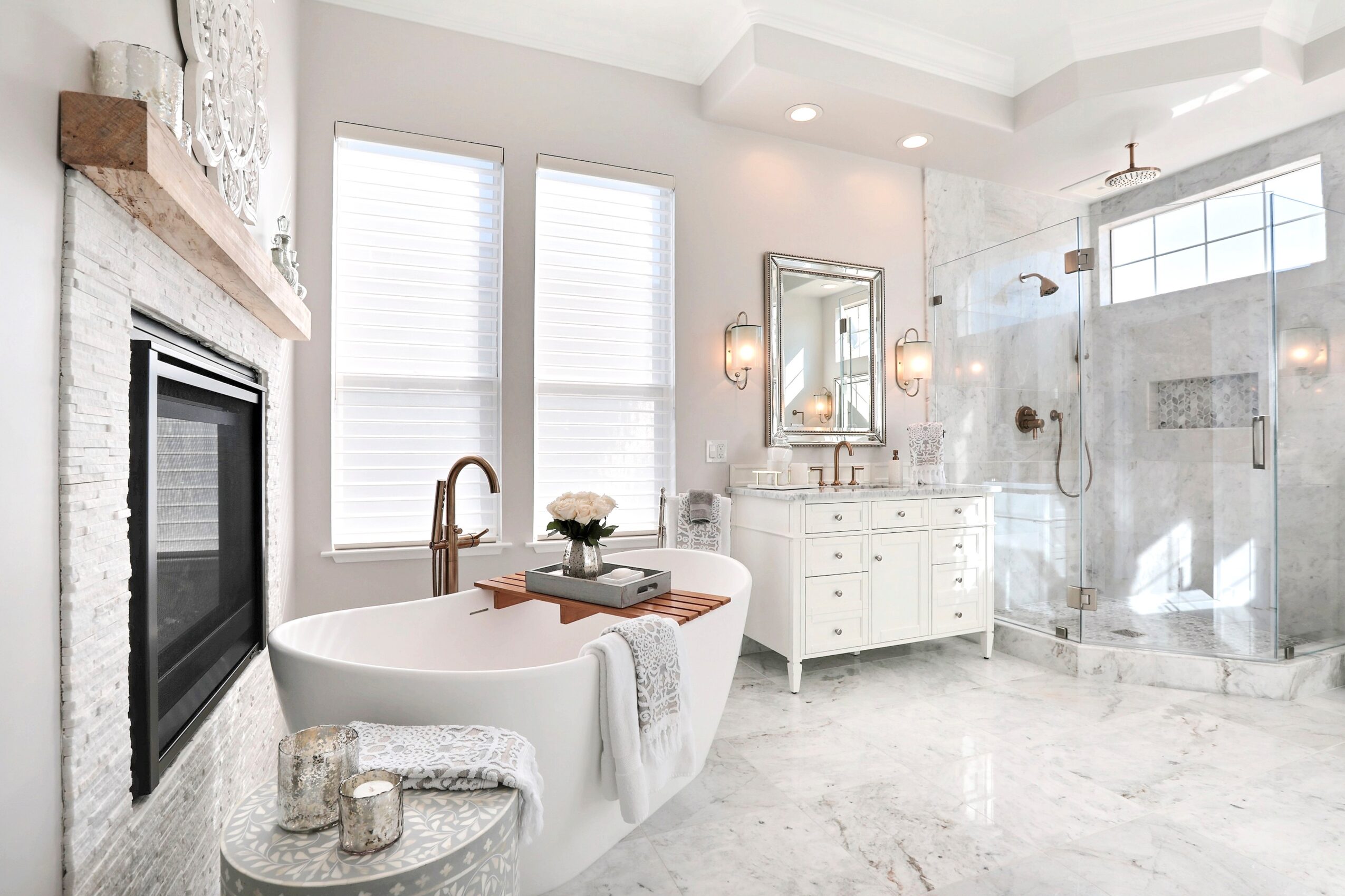 Bathroom with bathtub, vanity, mirror, and glass shower enclosure, bright with natural light from windows.