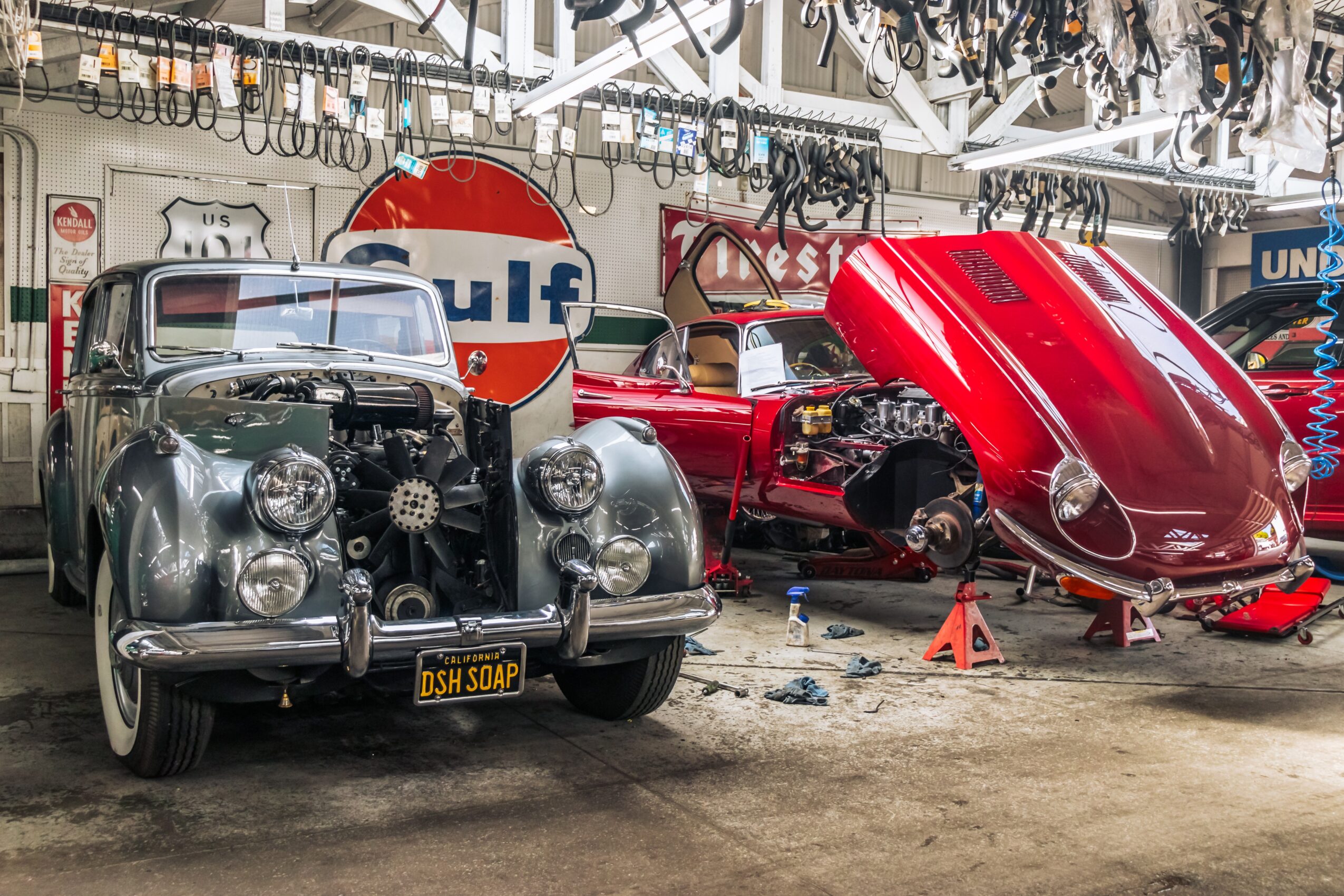 Vintage car and boat inside a garage with Gulf sign, tools, and equipment visible in the background.