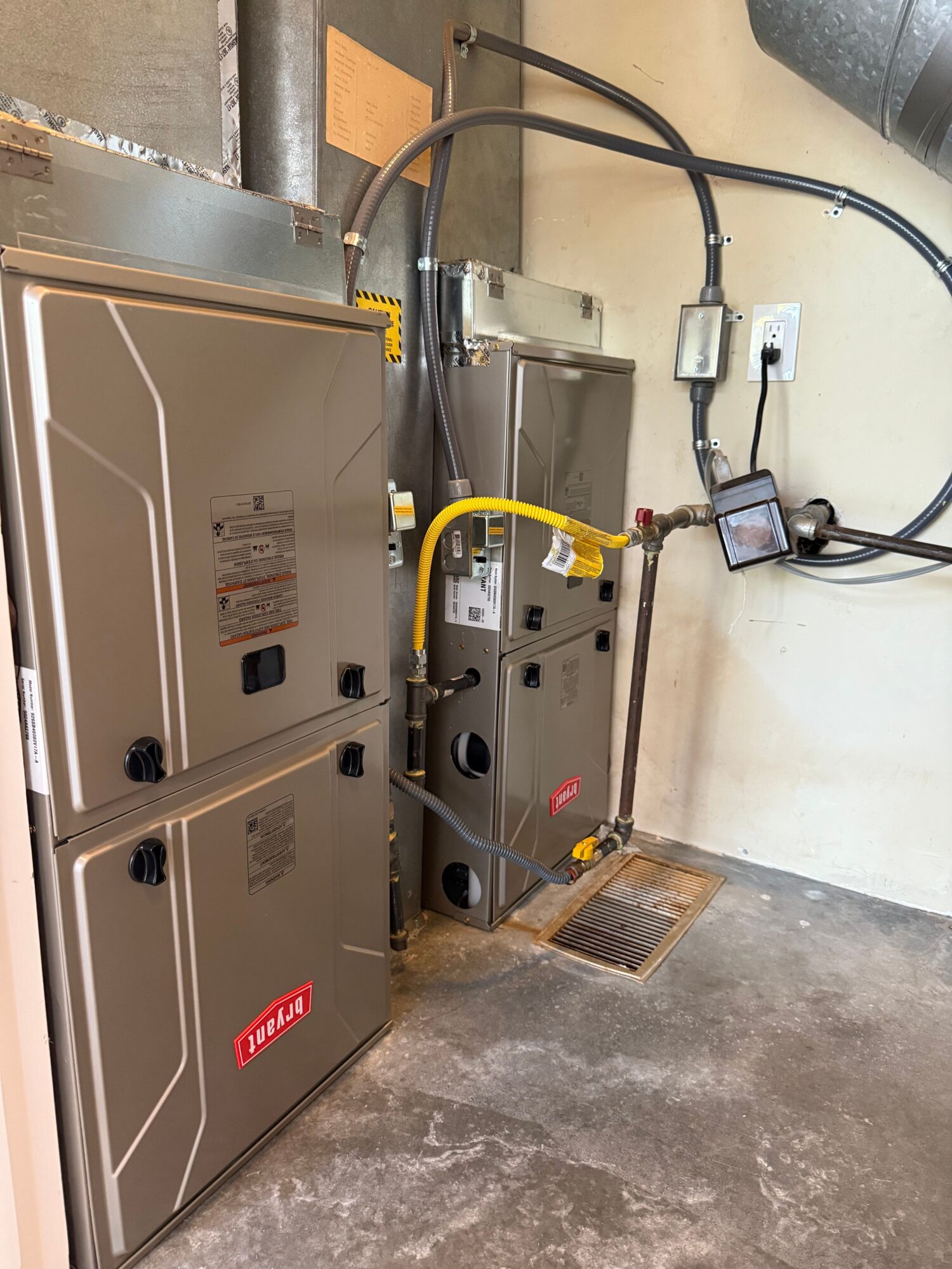 Electrical and utility equipment mounted on a wall, with cables and a monitor, in an industrial setting.