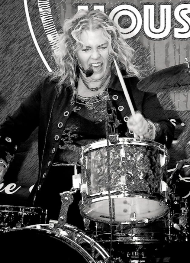 Woman playing drums, mouth open, holding drumstick, curly hair, energetic expression, black and white photo.