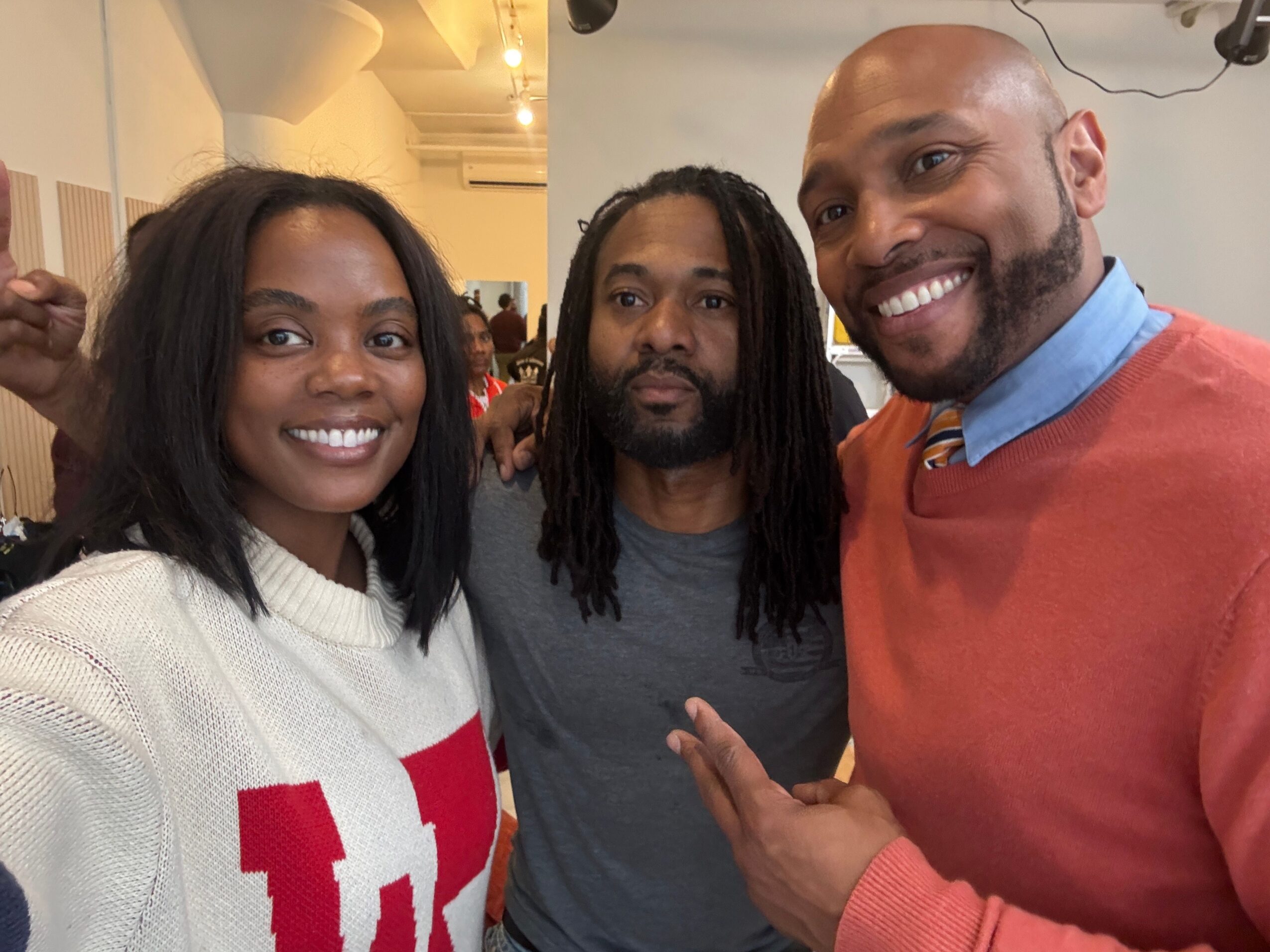 Three people smiling and posing for a photo indoors, with two men and one woman, all looking at the camera.