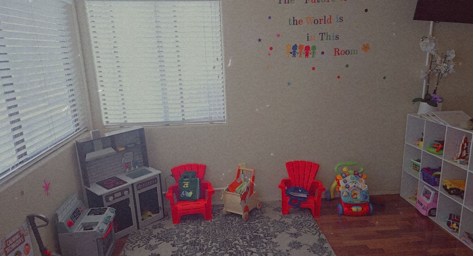 Children's playroom with chairs, toys, and storage shelves, illuminated by windows with blinds.