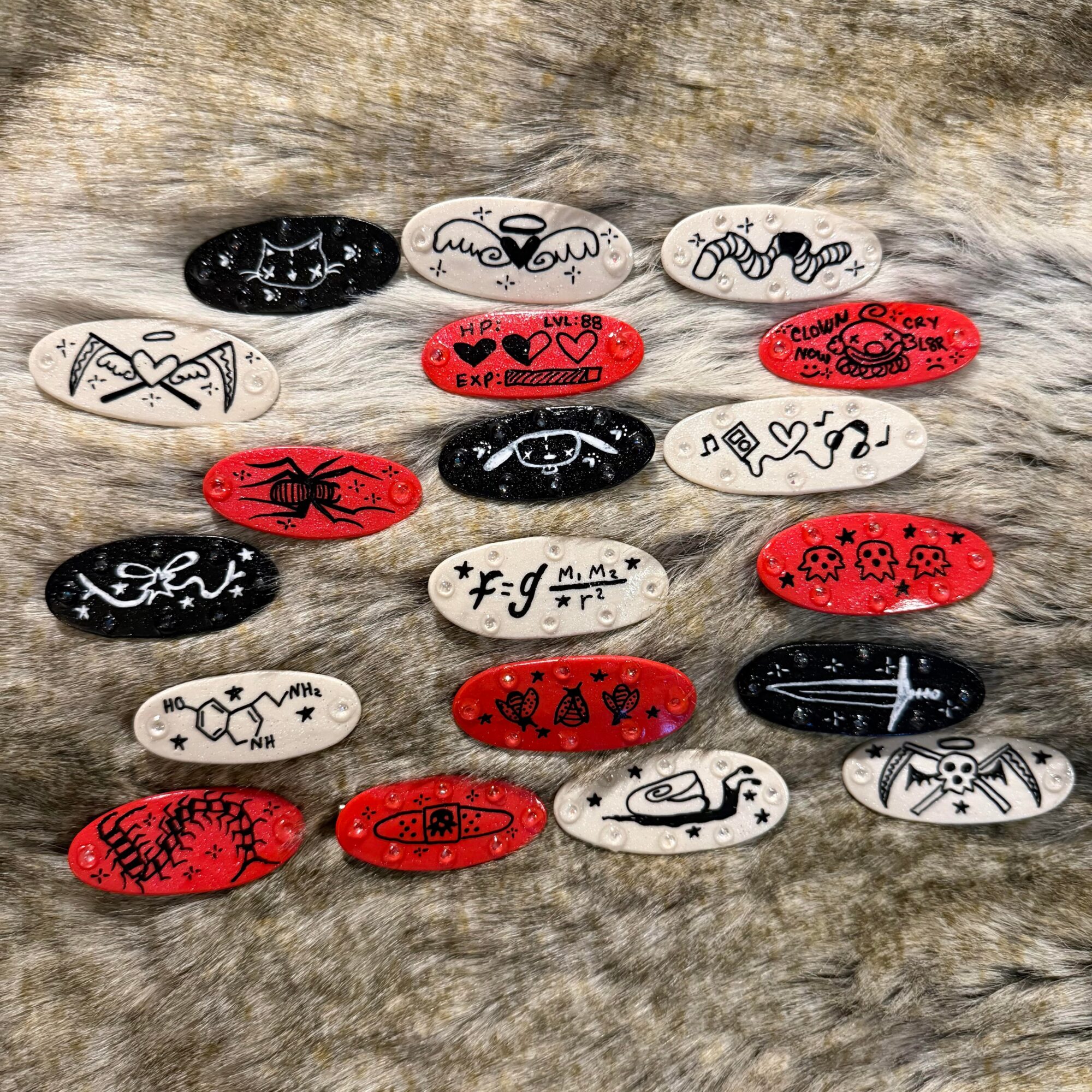 Collection of decorated oval stones with various black, red, and white designs and symbols on a textured surface.