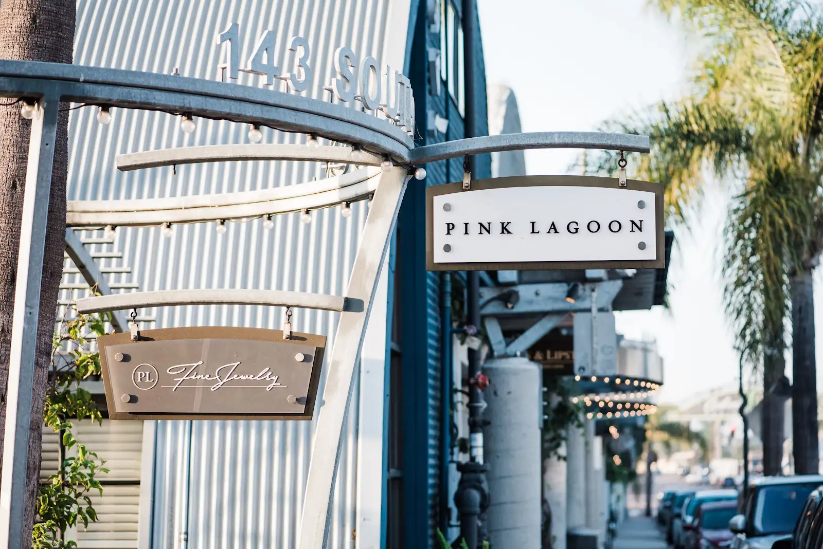 Sign for Pink Lagoon with palm trees in background, upright orientation, daytime.