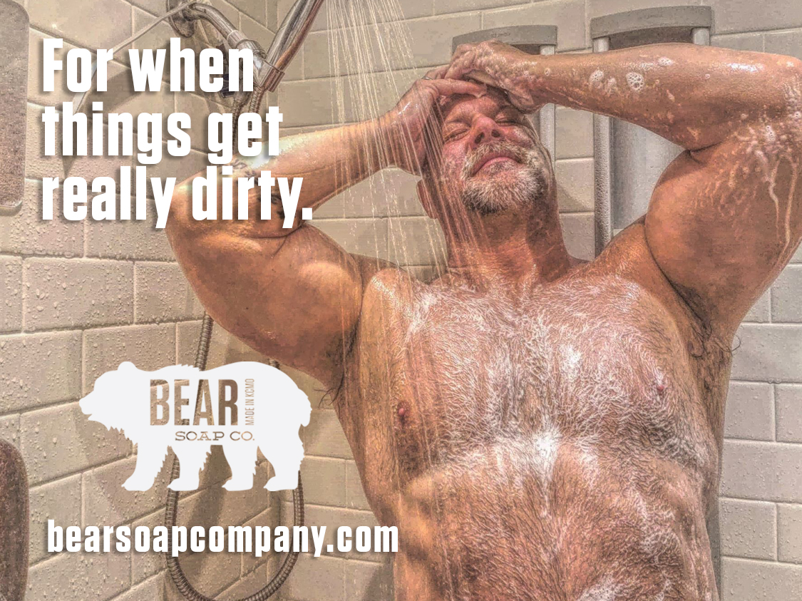 A man covered in soap suds with hands on his face in a shower, with text about dirt and a bear logo.