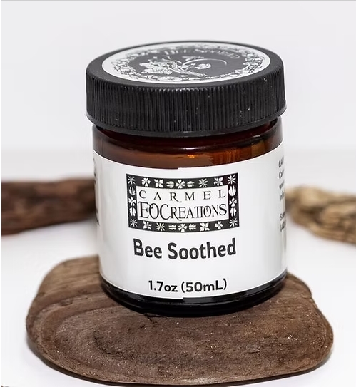 Small jar labeled 'Bee Soothed' on a wooden surface, with a white background.