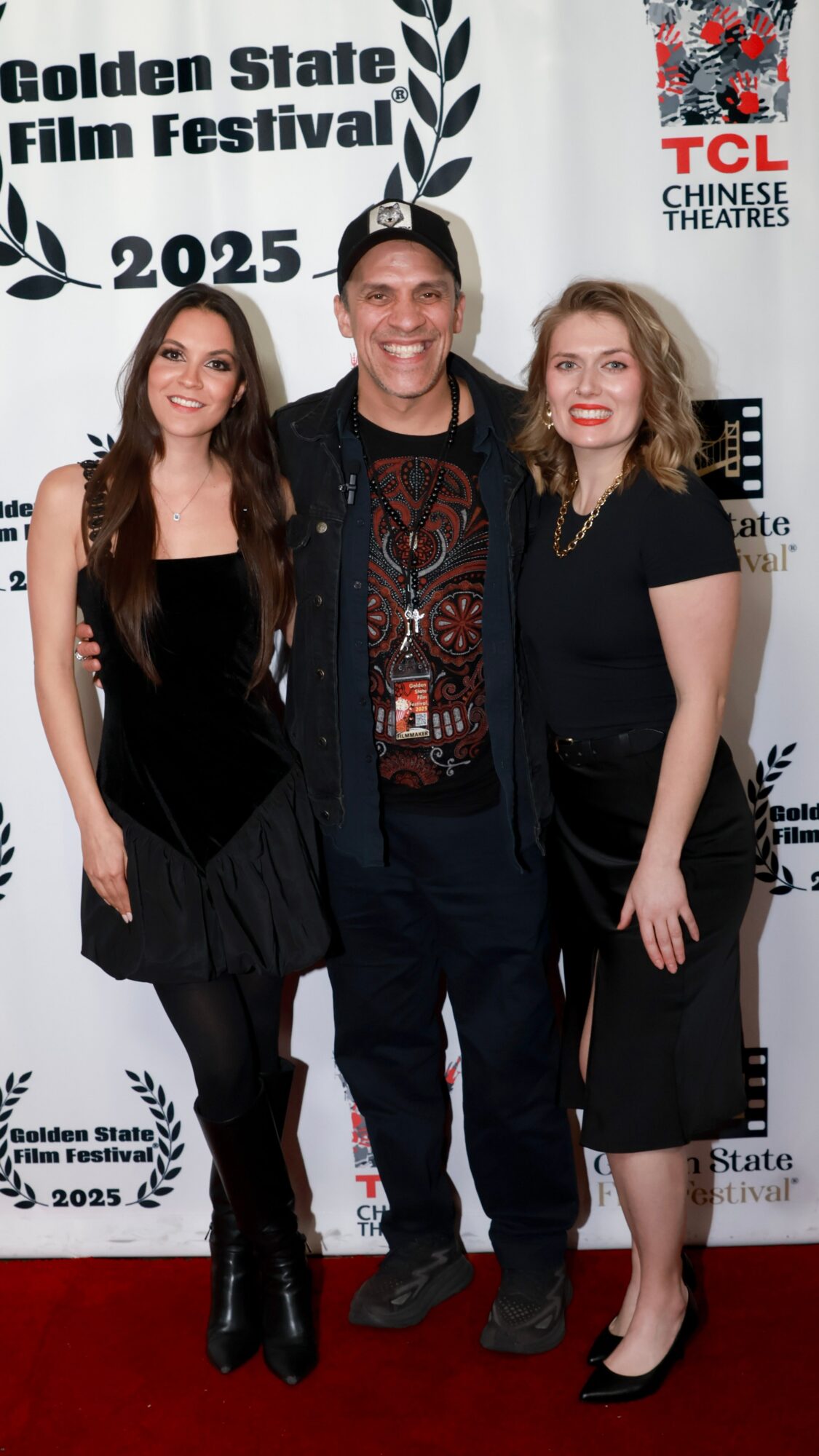Three people standing together at the Golden State Film Festival, smiling, with a backdrop featuring festival logos and text.
