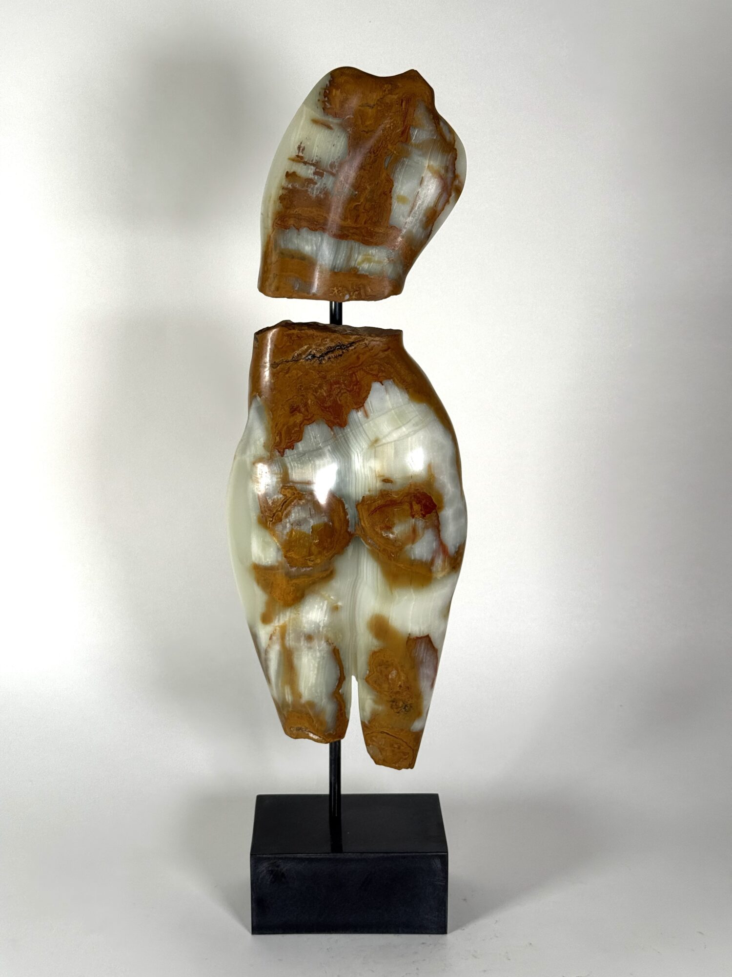 Abstract sculpture with two polished, irregularly shaped brown and white stone pieces mounted on a black base.