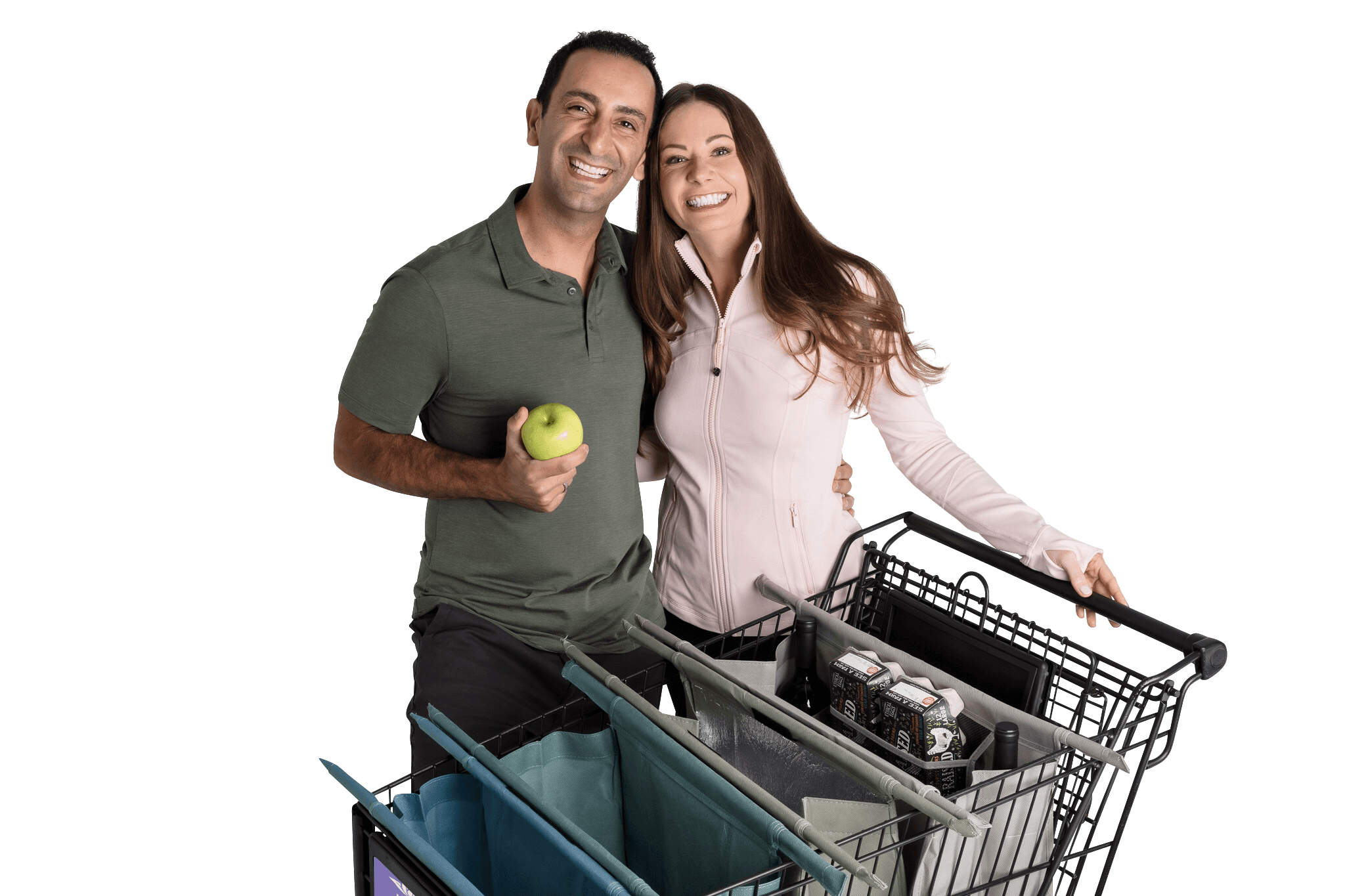 A smiling man and woman stand together holding shopping baskets, with the man holding an apple, against a black background.