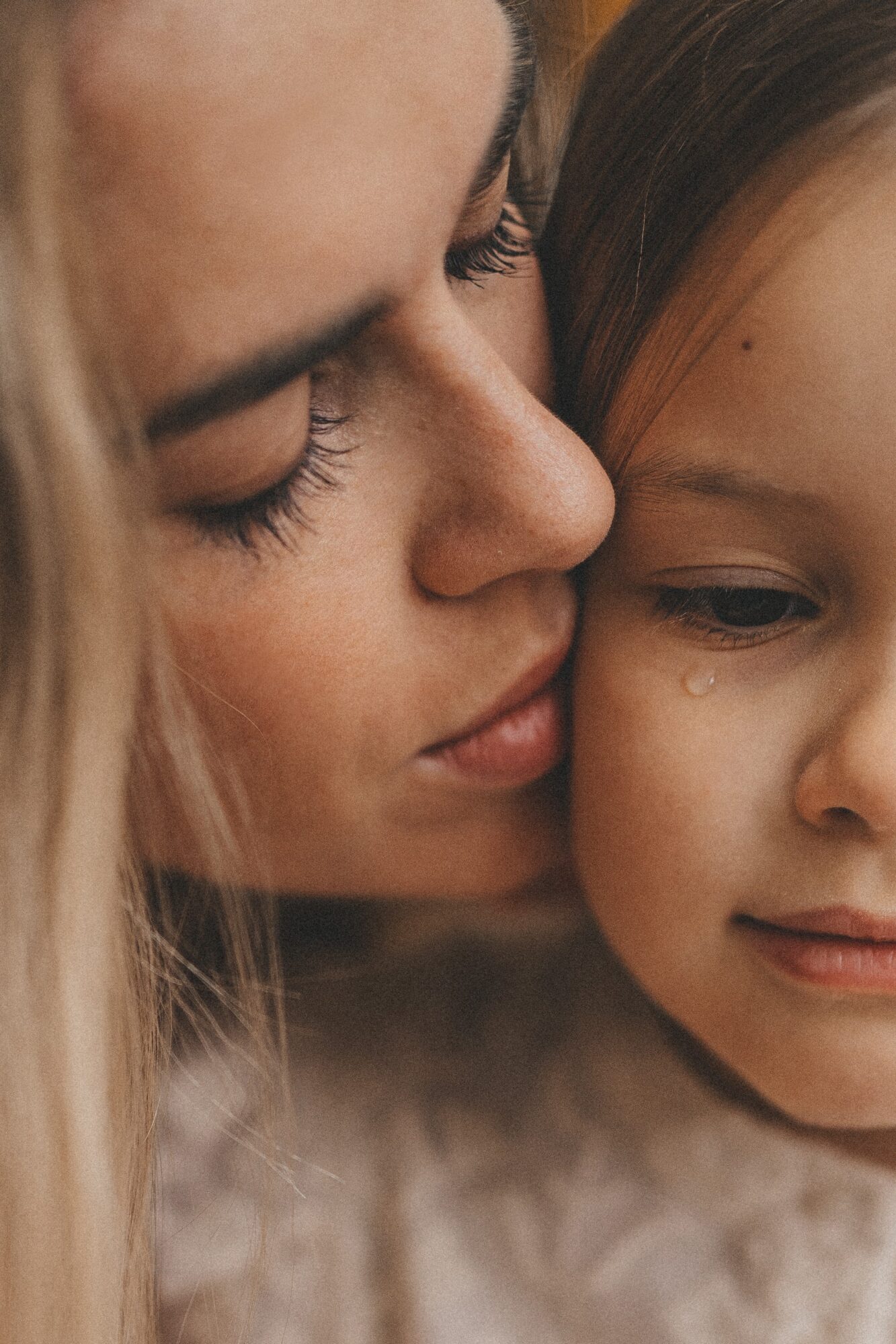 Close-up of two people, one kissing the other's cheek, with visible facial features and expressions.