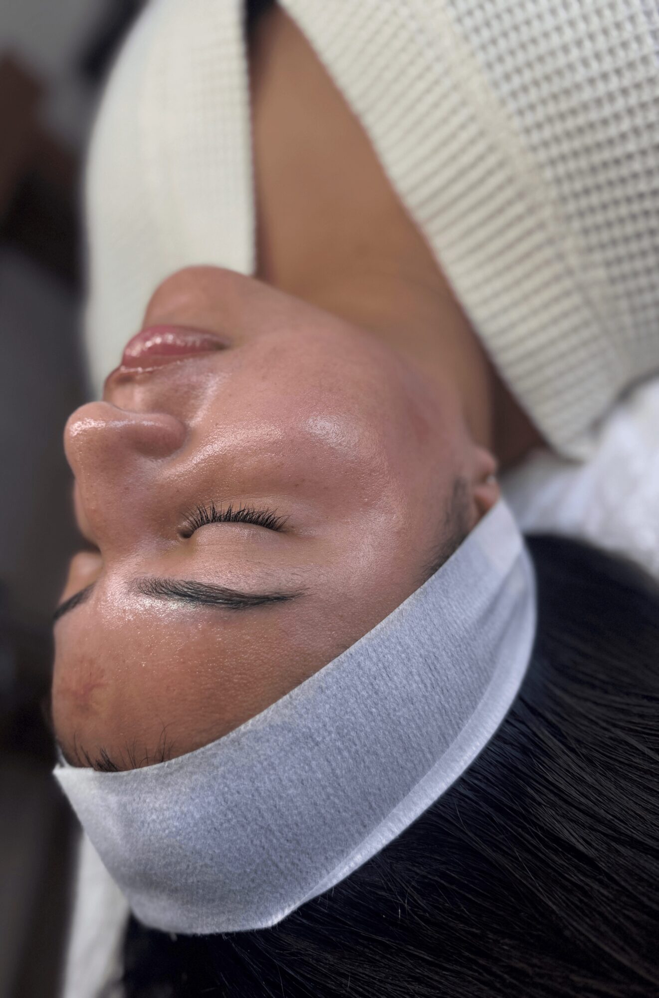 Person with closed eyes, wearing a headband and white garment, lying down with relaxed expression.