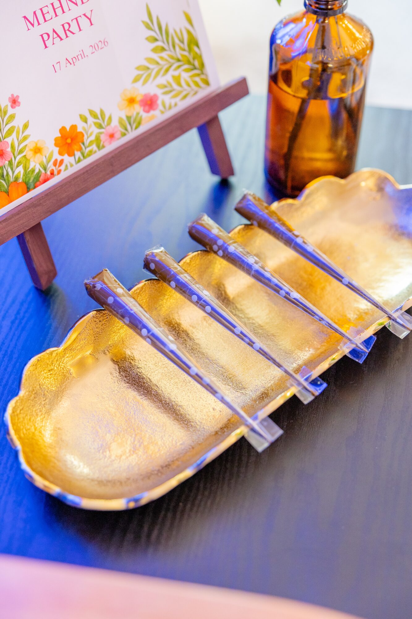 Golden tray with five small bottles and a cloud of smoke, on a dark surface, with a floral card and amber bottle in background.