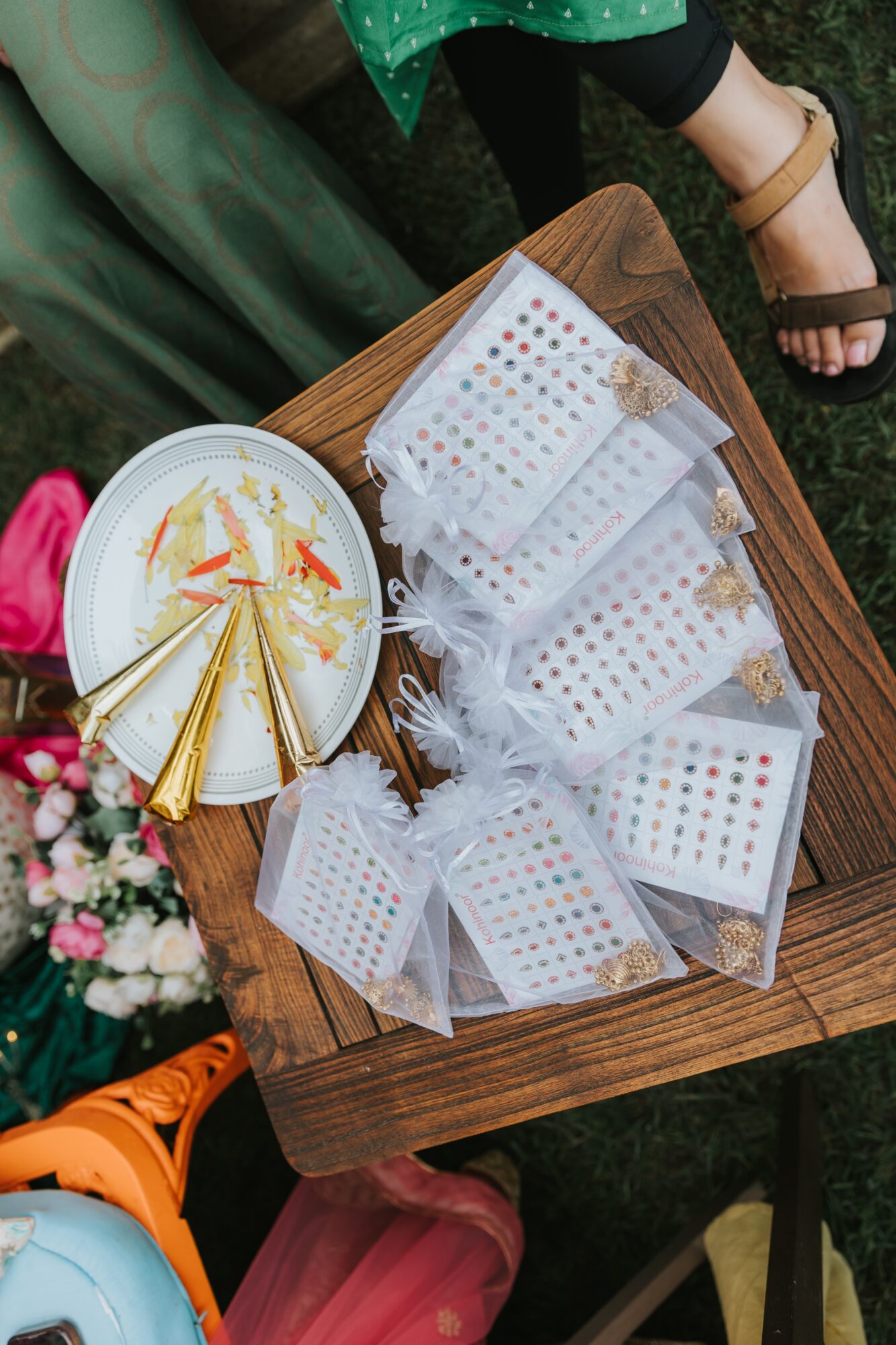 Table with white boxes, some with gold accents, and a plate with gold-wrapped items, outdoors setting with grass and shoes visible.