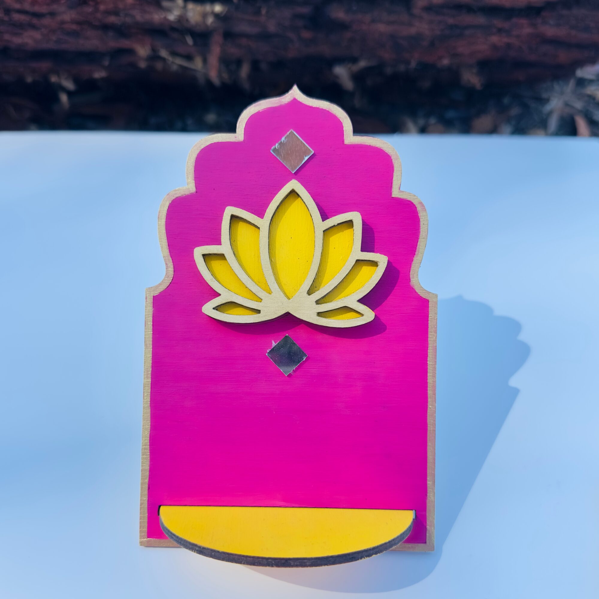 Decorative pink and yellow lotus-shaped object with geometric accents on a light blue background.