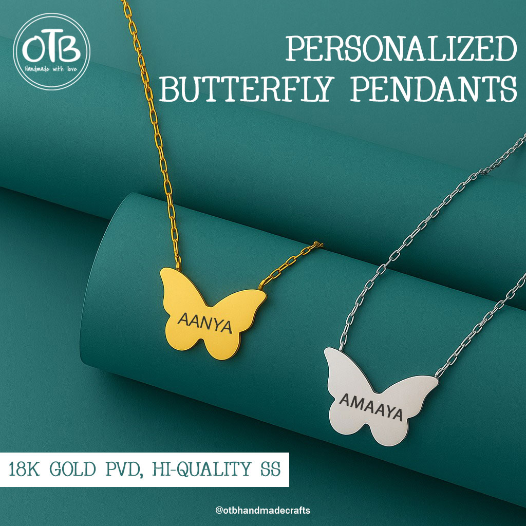Two butterfly-shaped pendants, one gold with 'AANYA' and one silver with 'AMAAYA', on chains, displayed on a teal background.