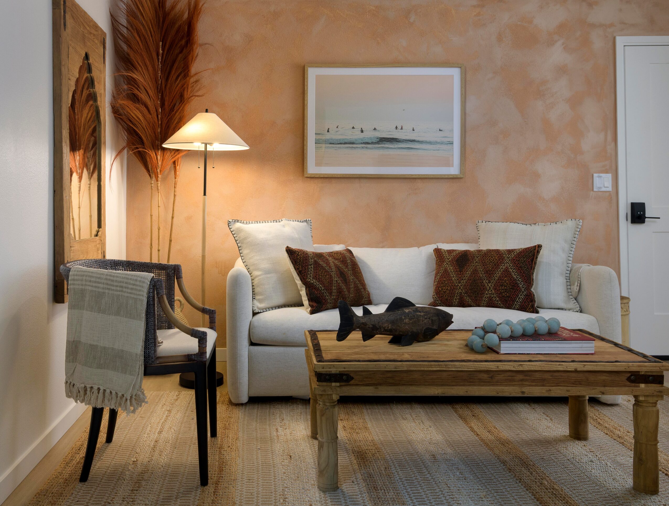 Living room with a white sofa, wooden coffee table, armchair, and wall art, warm lighting, and textured wall.