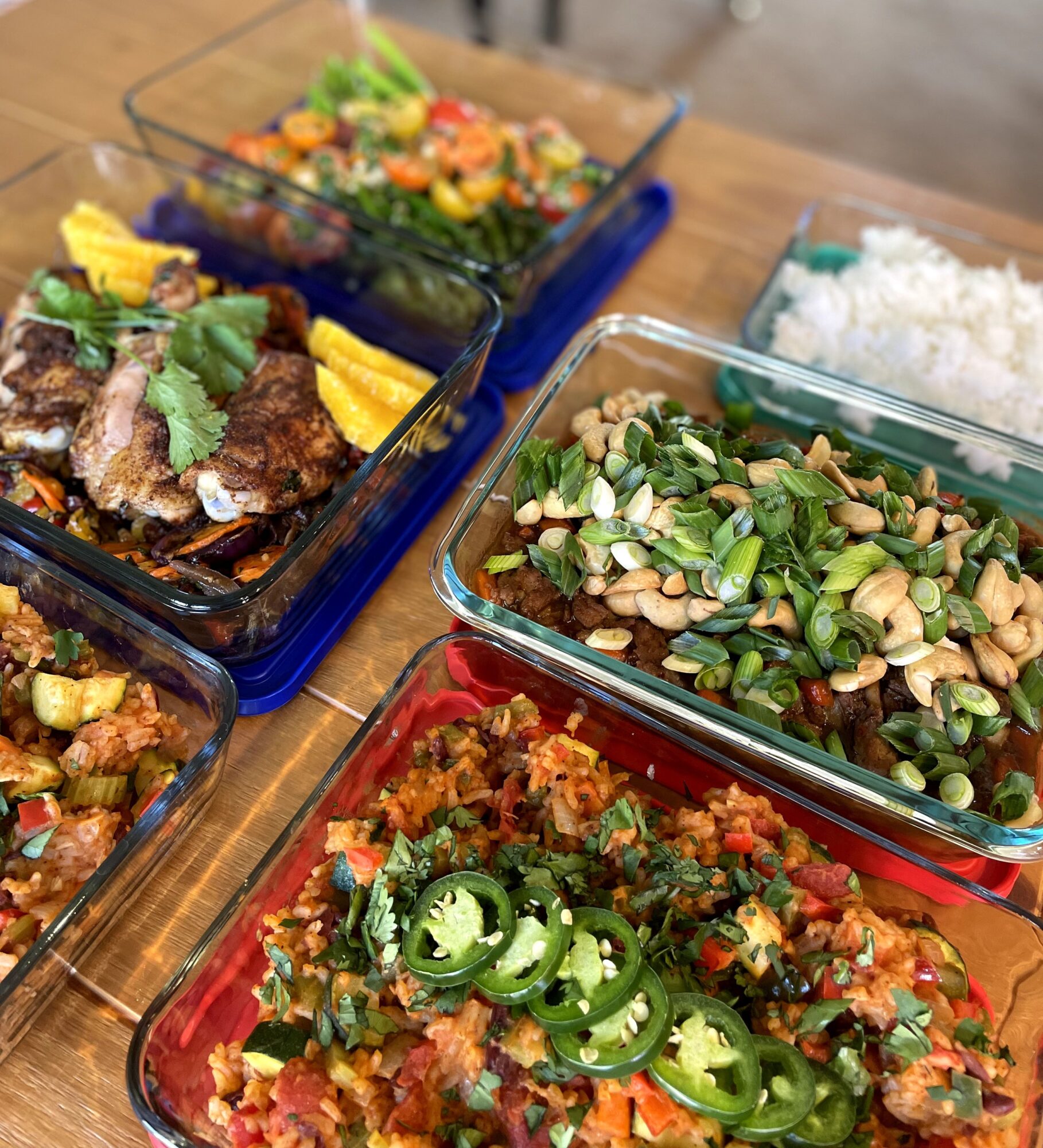 Assorted dishes including rice, salad, and cooked vegetables on a wooden table.